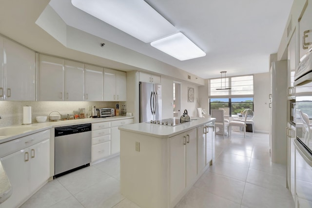 kitchen with stainless steel appliances, tasteful backsplash, hanging light fixtures, a kitchen island, and white cabinets