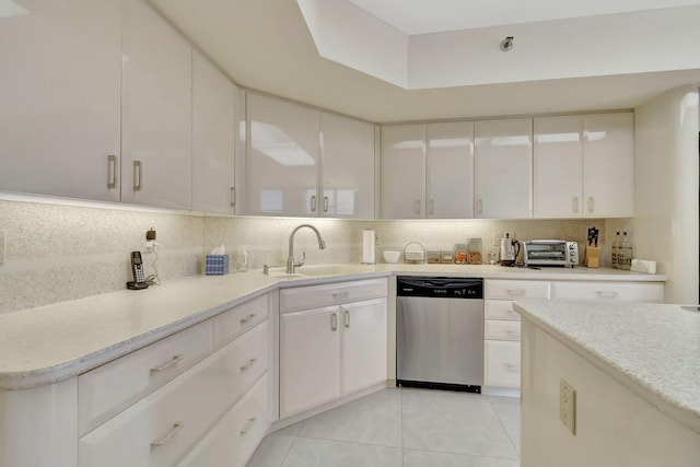 kitchen featuring white cabinetry, decorative backsplash, stainless steel dishwasher, and sink