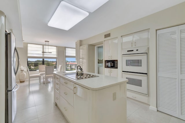 kitchen featuring stovetop, stainless steel fridge, white cabinetry, and a kitchen island