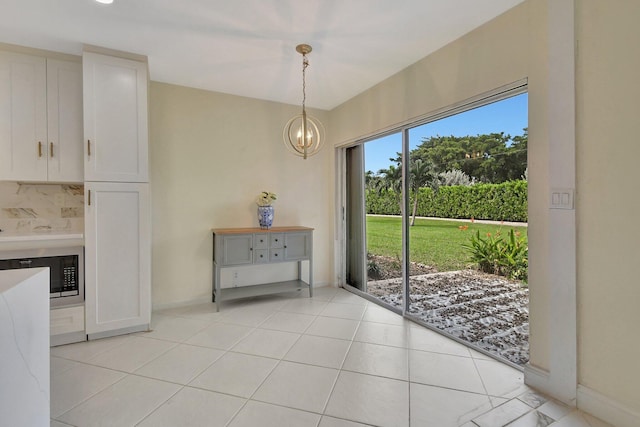 unfurnished dining area featuring light tile patterned floors and a chandelier