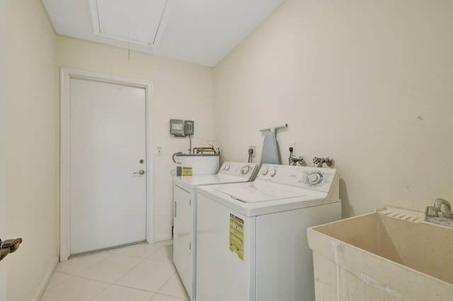 washroom featuring light tile patterned floors, electric water heater, sink, and washer and clothes dryer