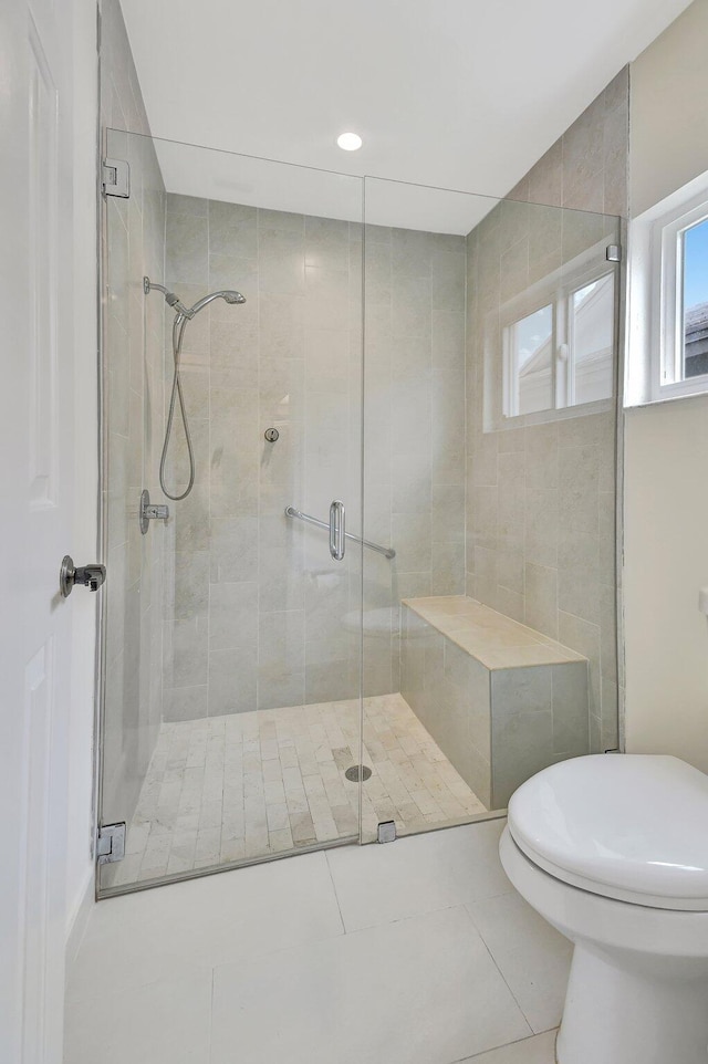 bathroom with a shower with door, toilet, and tile patterned flooring