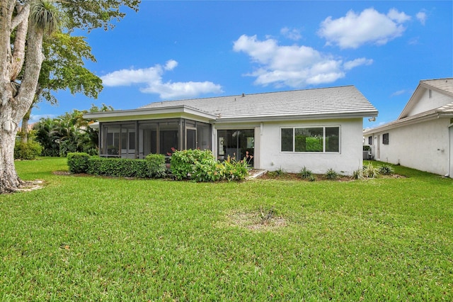 rear view of house featuring a yard and a sunroom