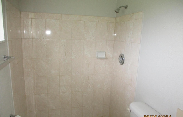 bathroom featuring tiled shower and toilet