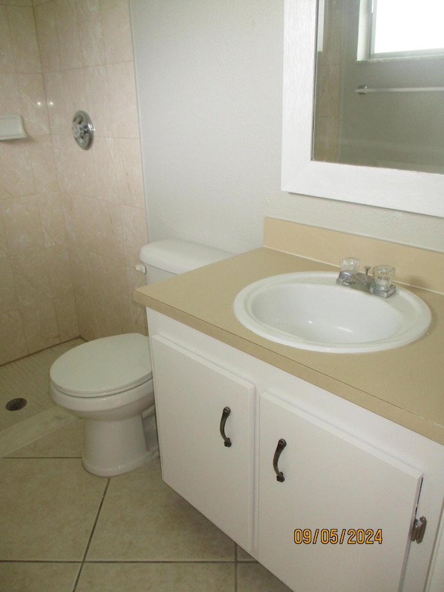 bathroom with tile patterned flooring, vanity, toilet, and tiled shower