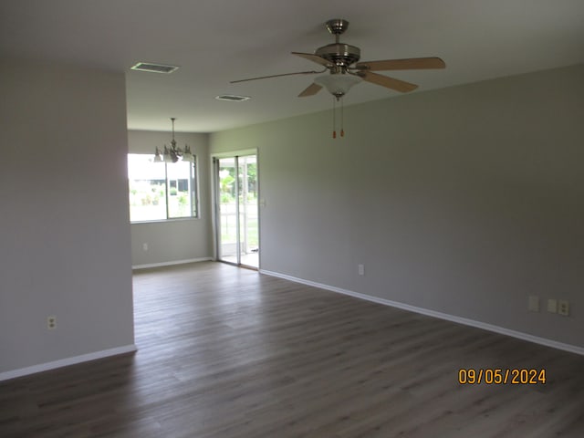 unfurnished room featuring dark hardwood / wood-style flooring and ceiling fan with notable chandelier