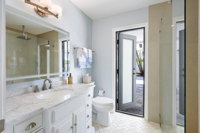 bathroom featuring a tile shower, vanity, toilet, and a wealth of natural light