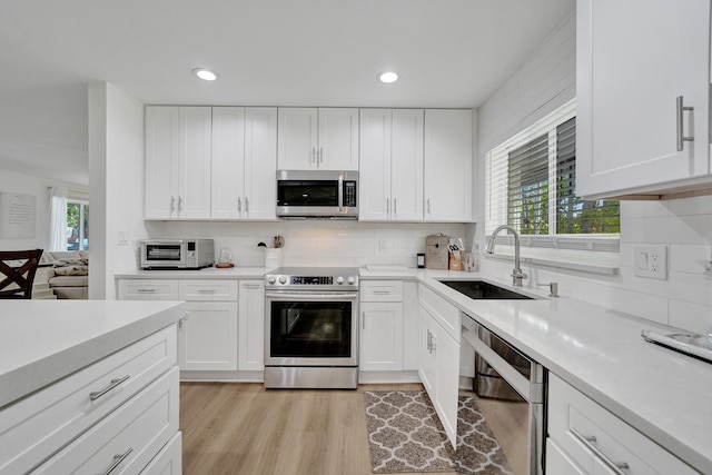 kitchen featuring white cabinets, a wealth of natural light, sink, and appliances with stainless steel finishes