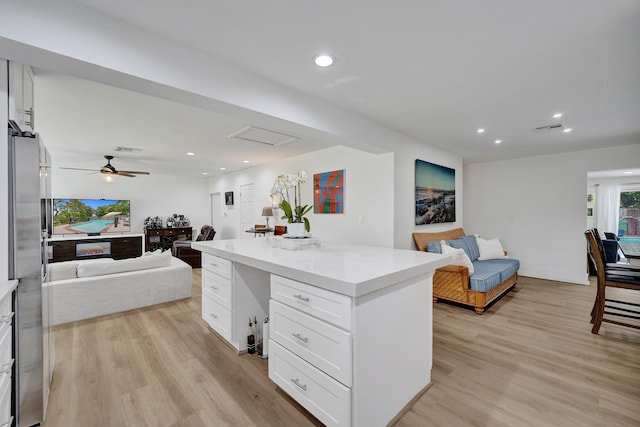 kitchen with ceiling fan, white cabinets, light wood-type flooring, and a kitchen island