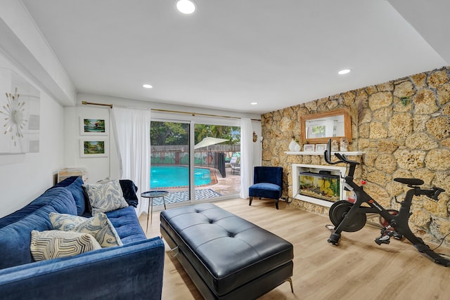 living room featuring a stone fireplace and light wood-type flooring