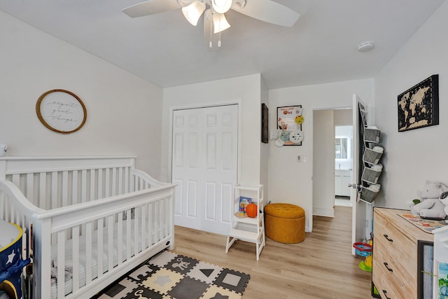 bedroom featuring ceiling fan, a closet, a nursery area, and light wood-type flooring