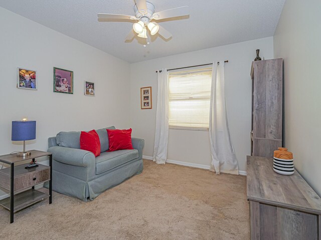 living area with light colored carpet, ceiling fan, and a textured ceiling