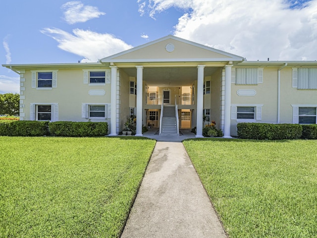 view of front of house with a front yard, stairway, and stucco siding