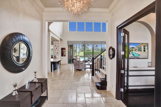 foyer with a towering ceiling, a notable chandelier, and ornamental molding