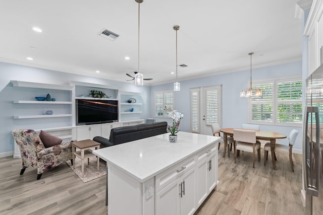 kitchen featuring french doors, a kitchen island, pendant lighting, white cabinets, and ceiling fan with notable chandelier