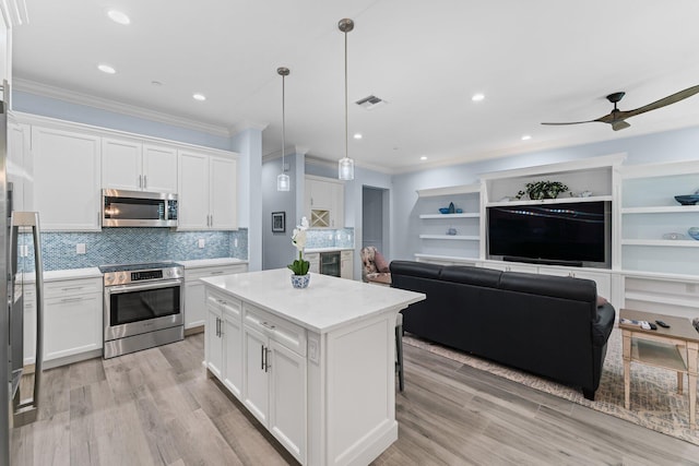 kitchen with white cabinets, a center island, pendant lighting, and appliances with stainless steel finishes