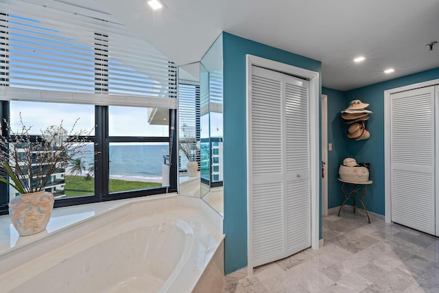 bathroom featuring a water view and a tub to relax in