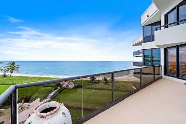 balcony with a water view and a view of the beach