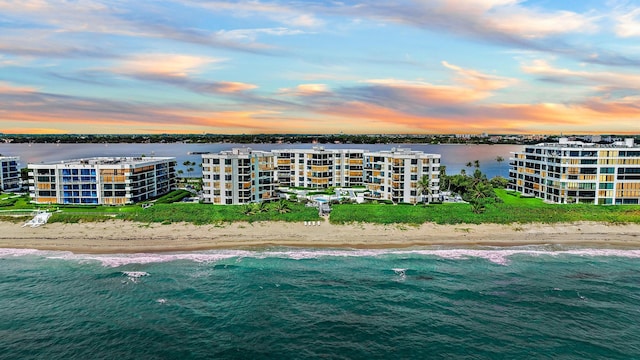 aerial view at dusk with a beach view and a water view