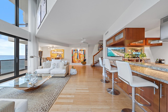 living room featuring ceiling fan, a healthy amount of sunlight, a water view, and light hardwood / wood-style flooring