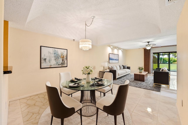 dining space with rail lighting, ceiling fan with notable chandelier, and a textured ceiling