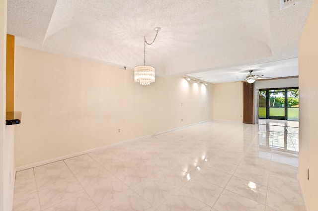 empty room featuring ceiling fan with notable chandelier and a textured ceiling