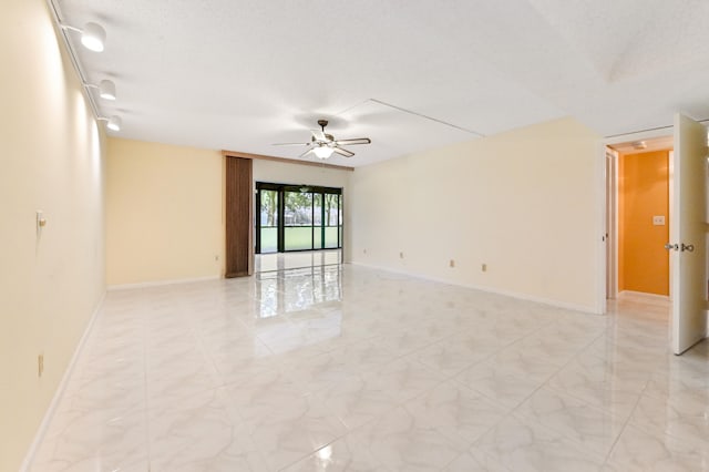 empty room with ceiling fan and a textured ceiling