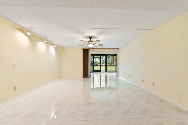 spare room with a textured ceiling, rail lighting, and ceiling fan