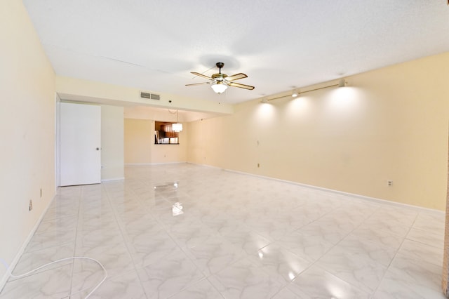 spare room featuring a textured ceiling, ceiling fan, and track lighting