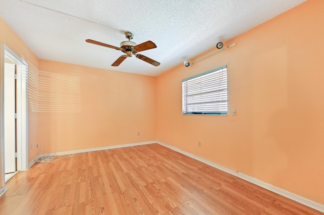 empty room featuring a textured ceiling, light wood-type flooring, and ceiling fan