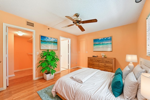 bedroom with a textured ceiling, light hardwood / wood-style floors, and ceiling fan