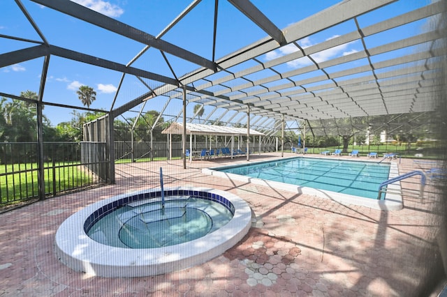 view of pool with an in ground hot tub, glass enclosure, and a patio area