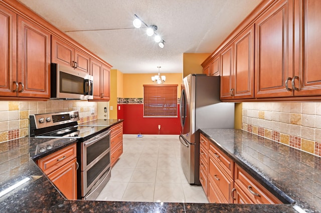 kitchen featuring stainless steel appliances, a chandelier, pendant lighting, decorative backsplash, and light tile patterned floors