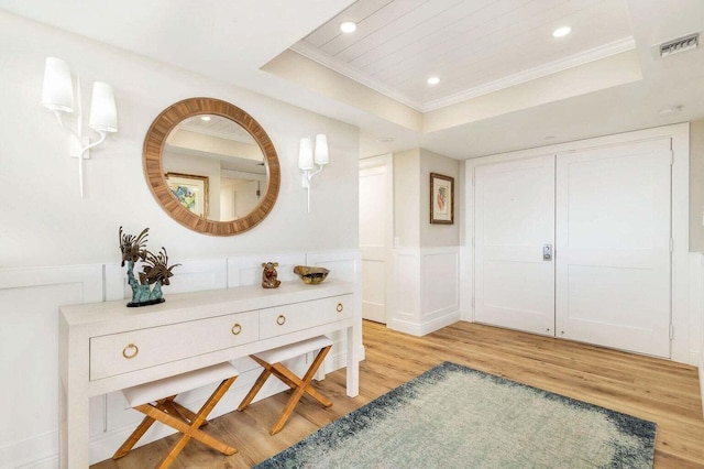 interior space featuring a tray ceiling, hardwood / wood-style flooring, and crown molding