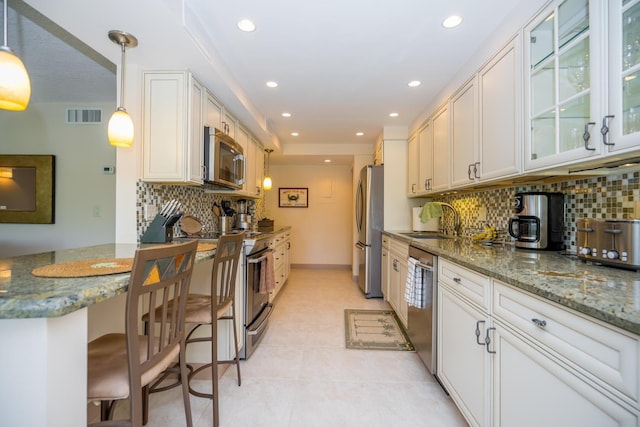 kitchen featuring backsplash, stainless steel appliances, sink, dark stone counters, and a kitchen bar