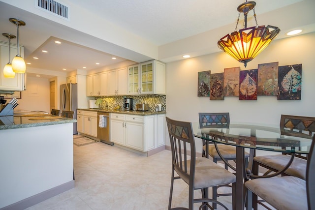 kitchen with white cabinets, light tile patterned floors, appliances with stainless steel finishes, light stone countertops, and decorative backsplash