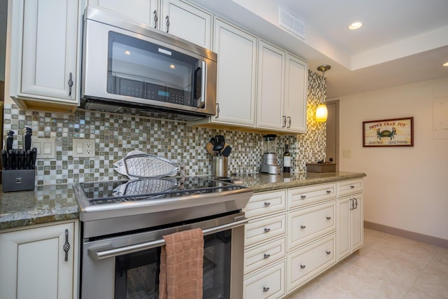 kitchen with light tile patterned floors, light stone countertops, stainless steel appliances, white cabinetry, and decorative backsplash