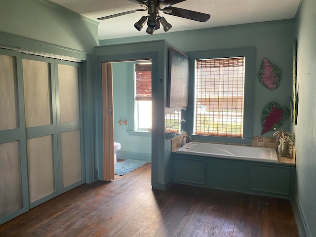 bathroom with ceiling fan, hardwood / wood-style floors, a bath, and toilet