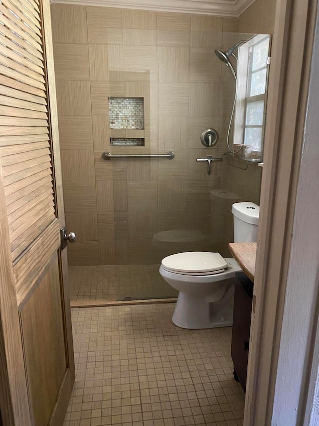 bathroom featuring a tile shower, vanity, crown molding, tile patterned flooring, and toilet