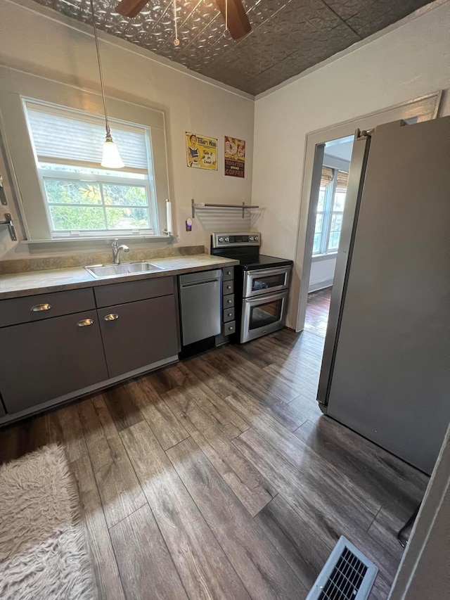 kitchen featuring appliances with stainless steel finishes, dark hardwood / wood-style floors, pendant lighting, and sink