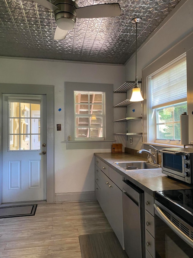 kitchen featuring appliances with stainless steel finishes, ceiling fan, sink, decorative light fixtures, and light hardwood / wood-style floors