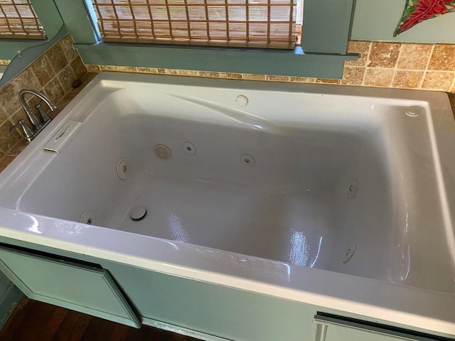 room details with a bath, backsplash, and hardwood / wood-style flooring