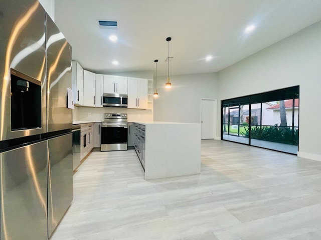 kitchen featuring hanging light fixtures, appliances with stainless steel finishes, and white cabinets