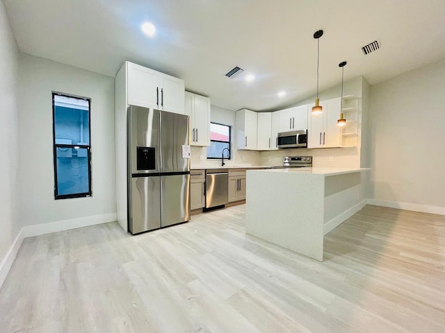 kitchen featuring pendant lighting, stainless steel appliances, light hardwood / wood-style floors, and kitchen peninsula