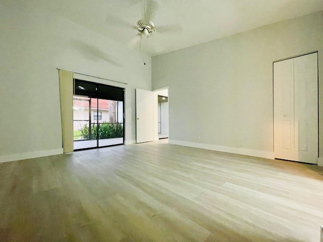 empty room featuring light hardwood / wood-style flooring, a high ceiling, and ceiling fan