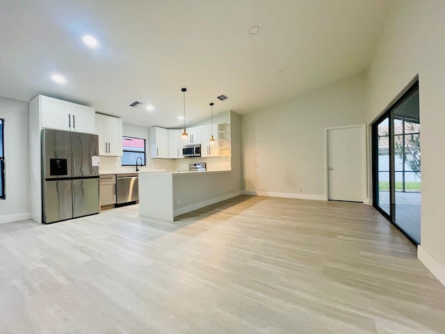 kitchen featuring light hardwood / wood-style flooring, decorative light fixtures, stainless steel appliances, vaulted ceiling, and white cabinets