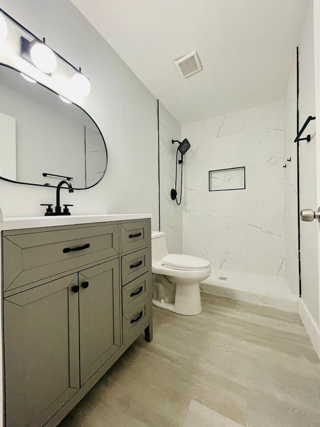 bathroom with vanity, toilet, and tiled shower