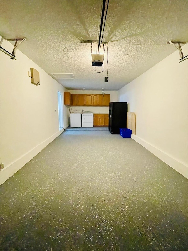 garage featuring a garage door opener, black refrigerator, and washer and clothes dryer