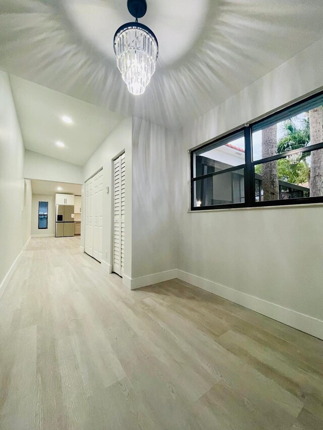 unfurnished room featuring vaulted ceiling and a notable chandelier