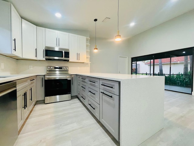 kitchen featuring appliances with stainless steel finishes, light hardwood / wood-style floors, kitchen peninsula, gray cabinets, and lofted ceiling